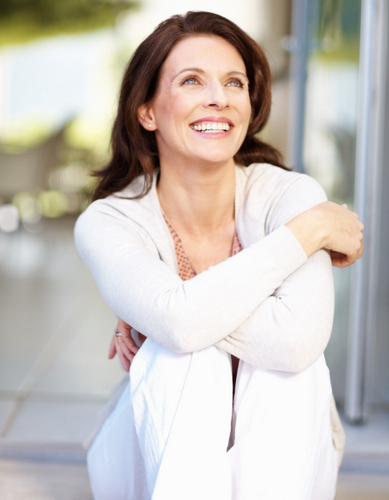 Woman hugging knees and smiling after receiving her new teeth in a day from Fairbanks Periodontal Associates in Fairbanks, AK