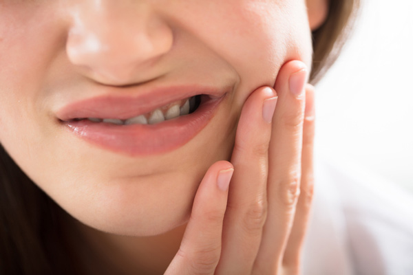 Female patient of Fairbanks Periodontal Associates holding jaw in Fairbanks, AK