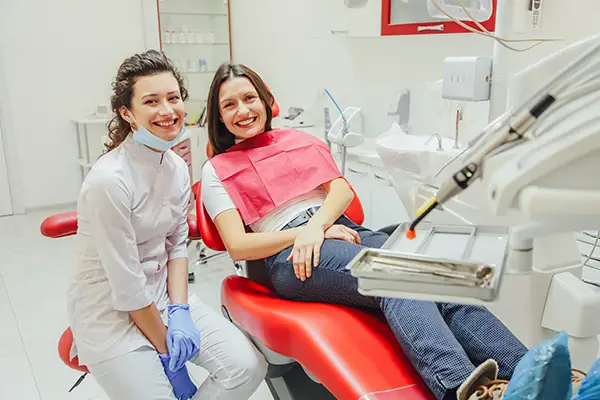 A dentist smiling brightly while explaining gum disease treatment process to her seated patient at Fairbanks Periodontal Associates in Fairbanks, AK